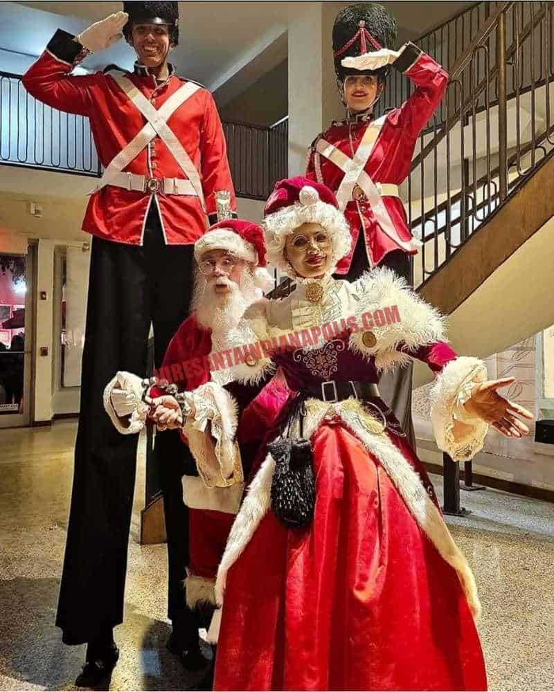 Hire Santa for a company Christmas party in Indianapolis: Santa, Mrs. Claus, and two stilt nutcrackers indoors.