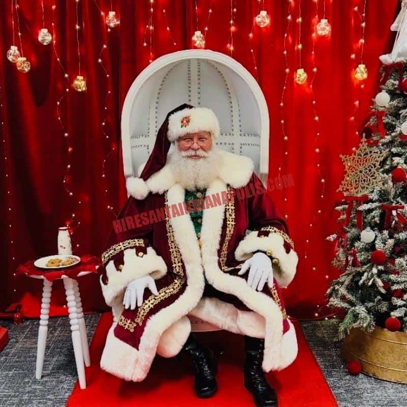 Santa for hire in Carmel, IN: real bearded Santa in a white chair with cookies and milk beside a tree.