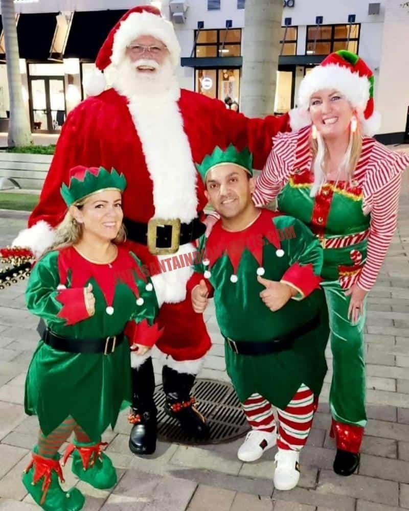 Santa for hire in Greenwood, IN: Santa outdoors at dusk with three elves on pavers.